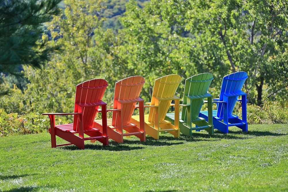 sillas de madera Adirondack en colores rojo, naranja, amarillo, verde y azul