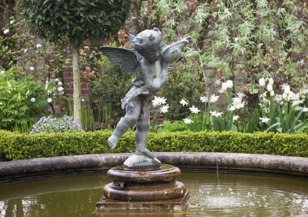 Estanque y fuente con escultura en romántico jardín inglés