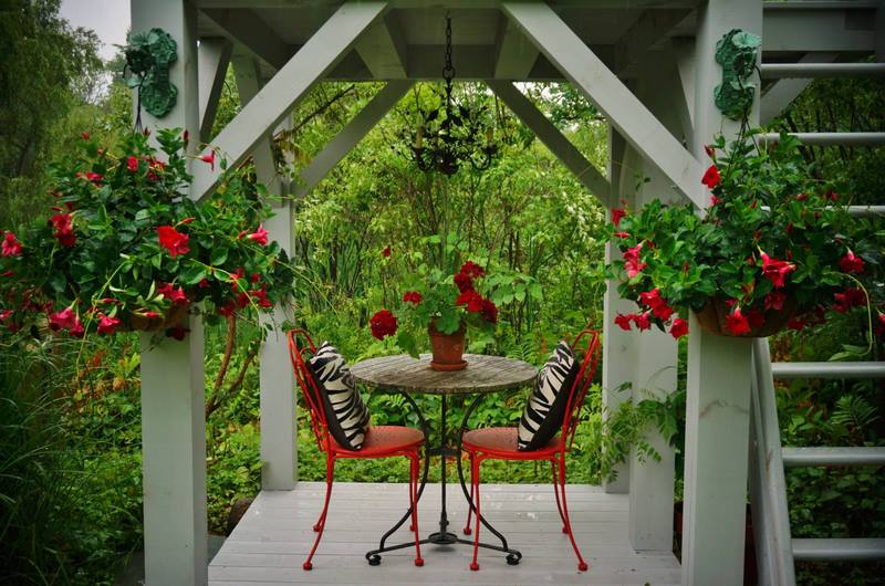 porche con columnas blancas, mesas, sillas y plantas en rojo