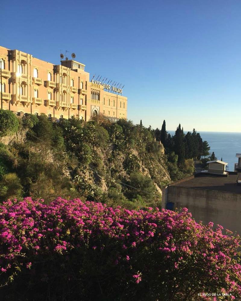 Flores rosas y vista de Taormina en Sicilia